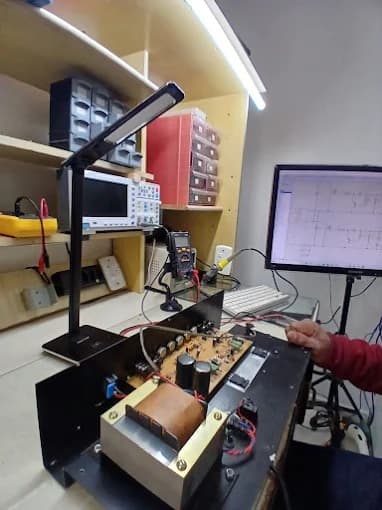 Amplificador valvulado aberto na bancada, ao lado do osciloscópio